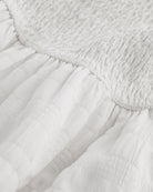 Close-up of white smocked fabric and gathered waist detail on Stelle girls dress.