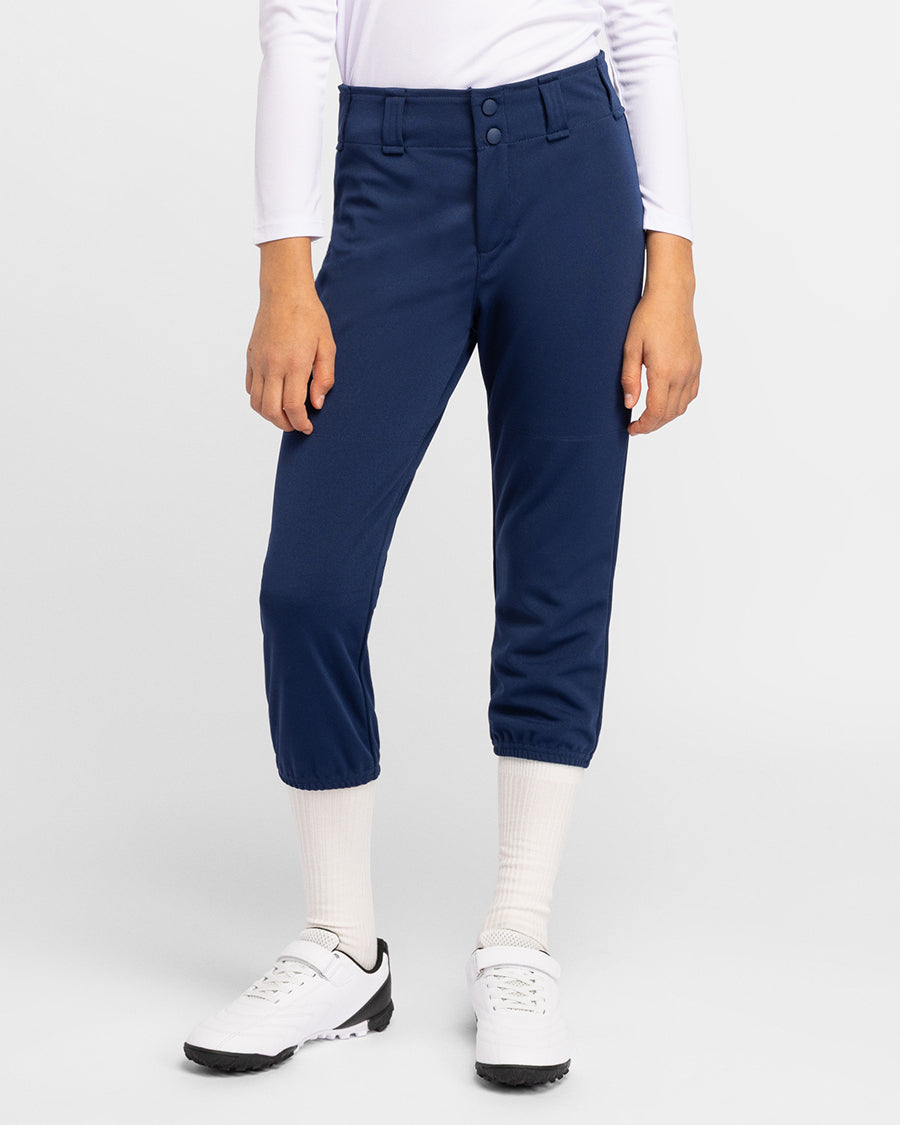 Person wearing navy blue pants with a white shirt and white shoes on a light gray background