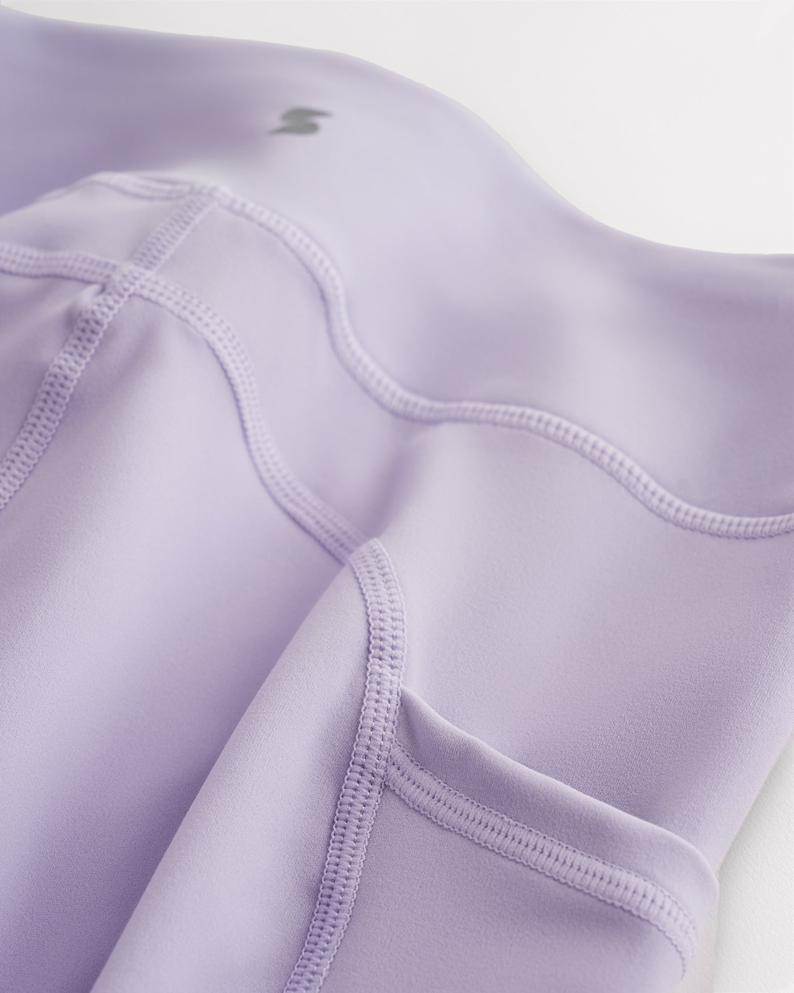 Close-up of lavender girls flare leggings showing soft 4-way stretch fabric, waistband seam, side pocket detail, and small Stelle logo.