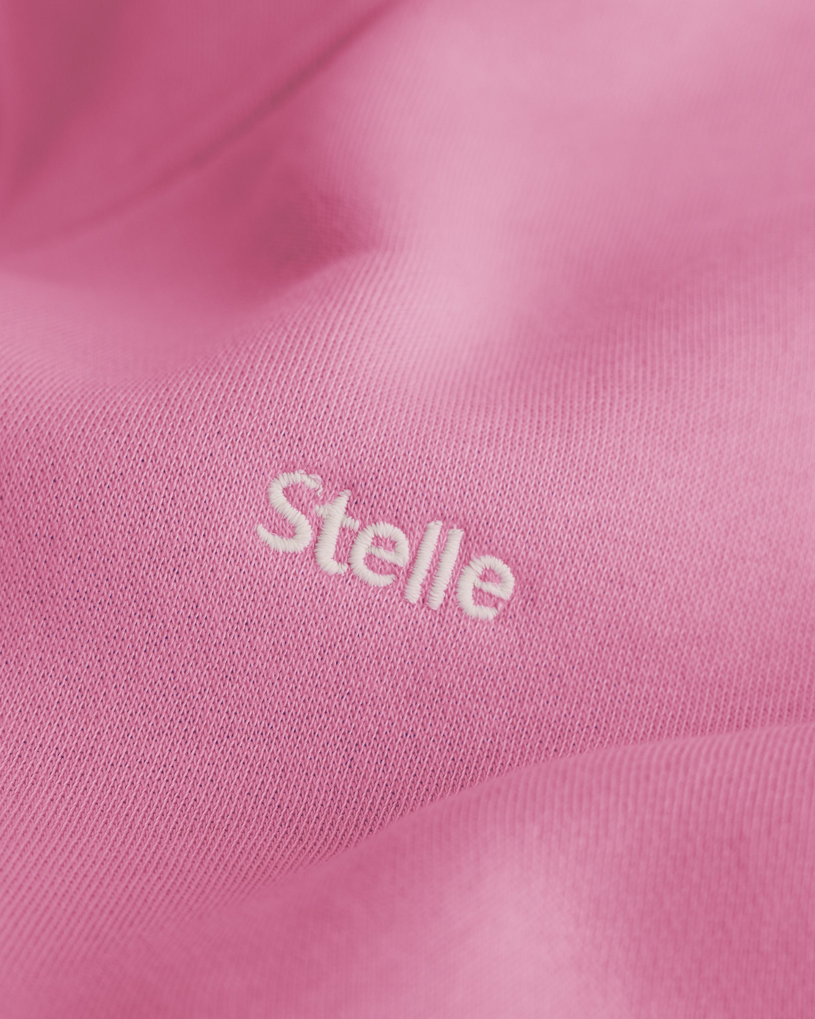 Close-up of the embroidered Stelle logo on the orchid fleece hoodie.