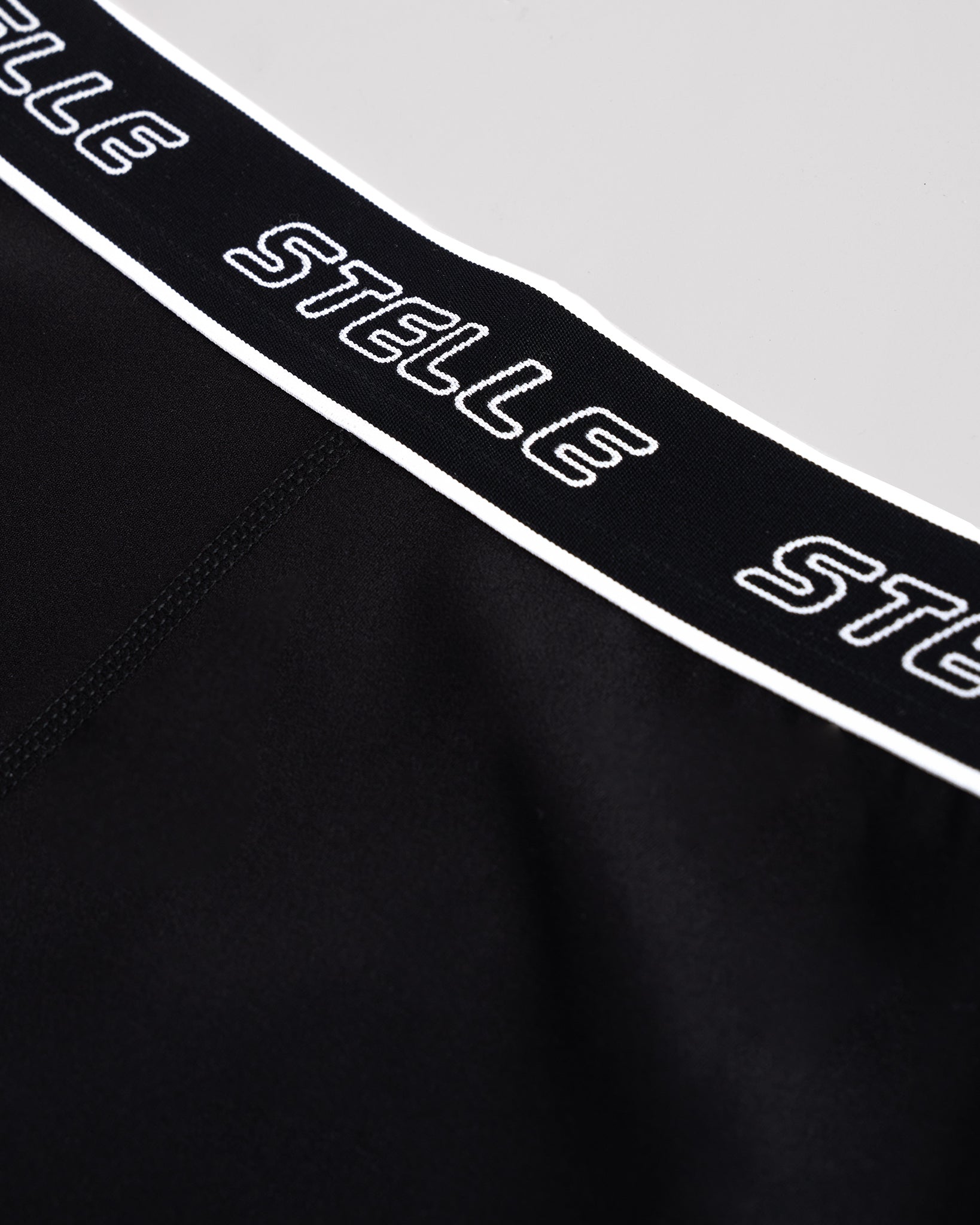 Detail of the repeating Stelle logo on the elastic waistband of the black girls leggings.