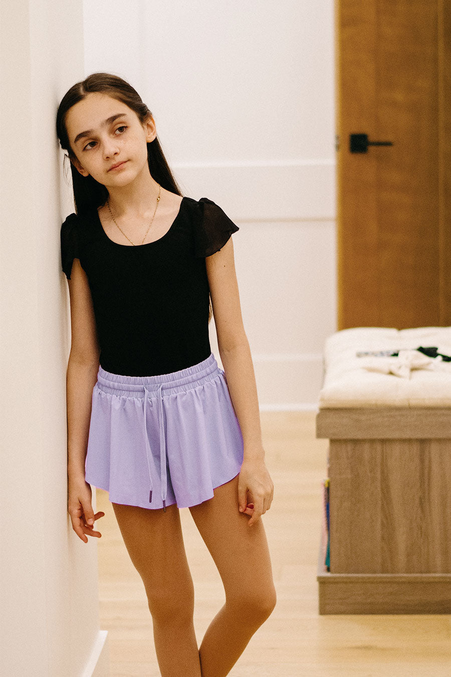 Girl wearing black leotard and purple butterfly shorts