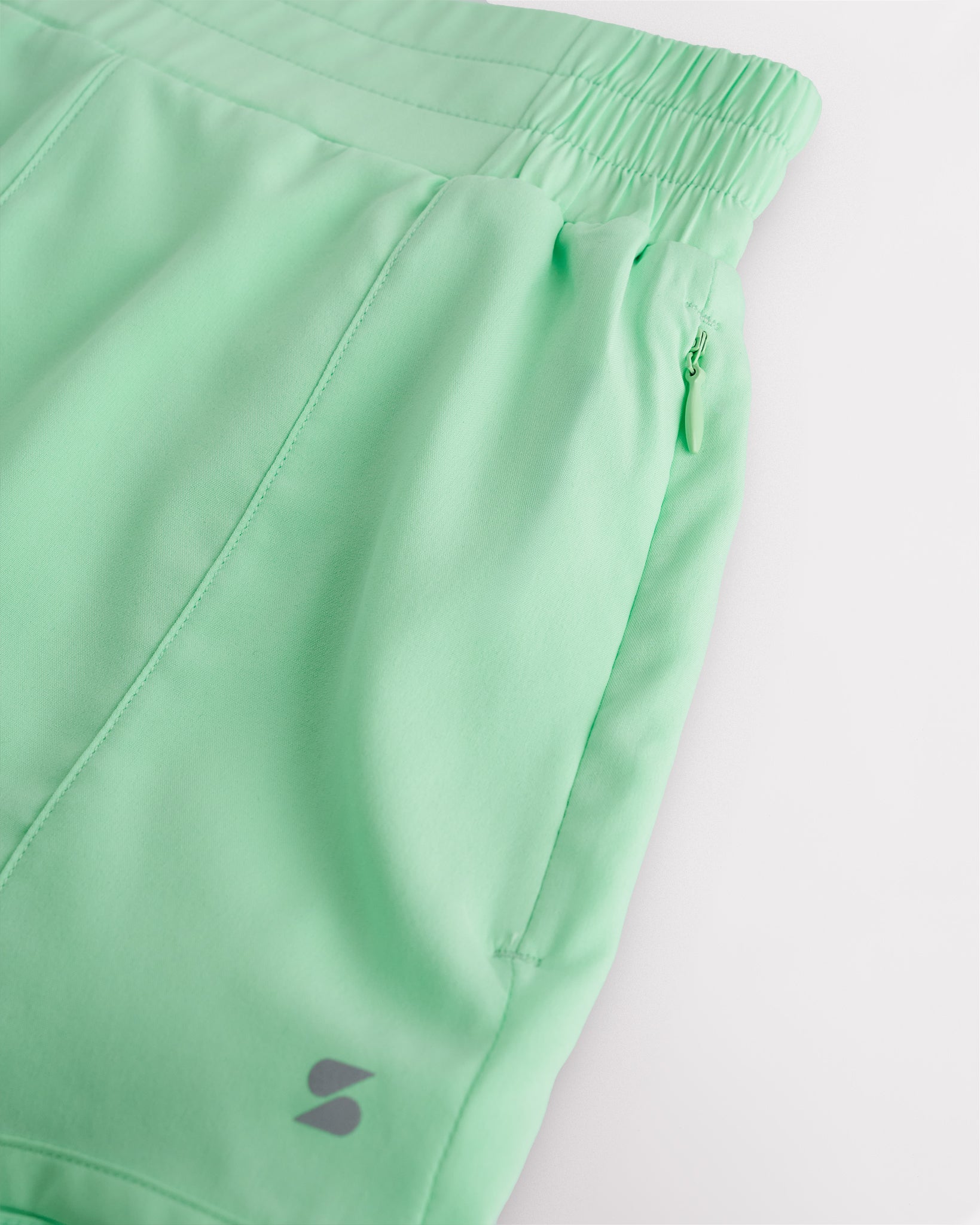 Close-up of girls athletic shorts showing soft stretchy material, elastic waistband, and zip pocket detail
