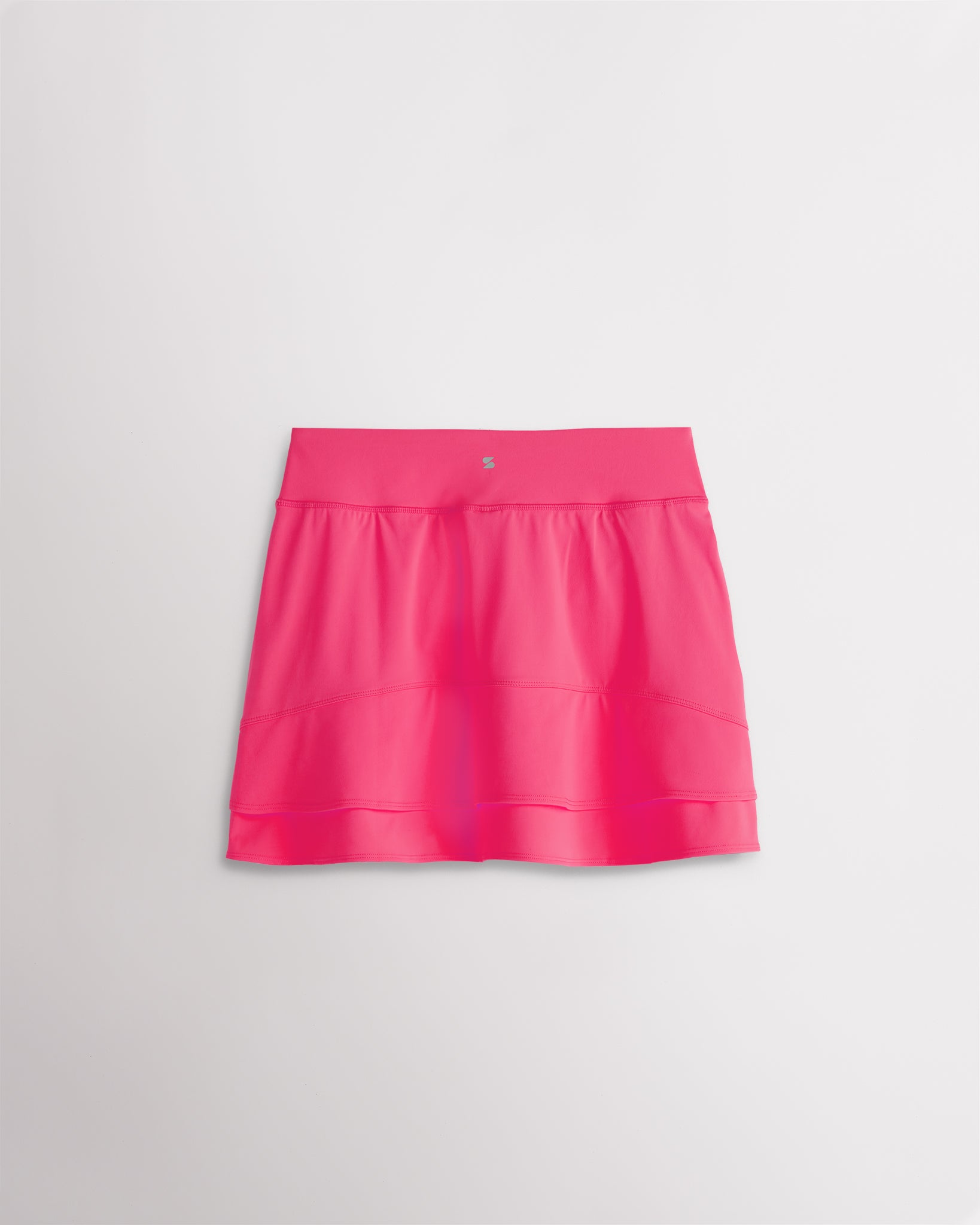 A quick-dry dreamhouse pink tennis skirt with a smooth front, ruffle back hem, and built-in shorts with pockets for comfortable coverage on and off the court.