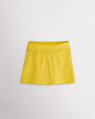 A quick-dry yellow tennis skirt with a smooth front, ruffle back hem, and built-in shorts with pockets for comfortable coverage on and off the court.