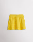 A quick-dry yellow tennis skirt with a smooth front, ruffle back hem, and built-in shorts with pockets for comfortable coverage on and off the court.