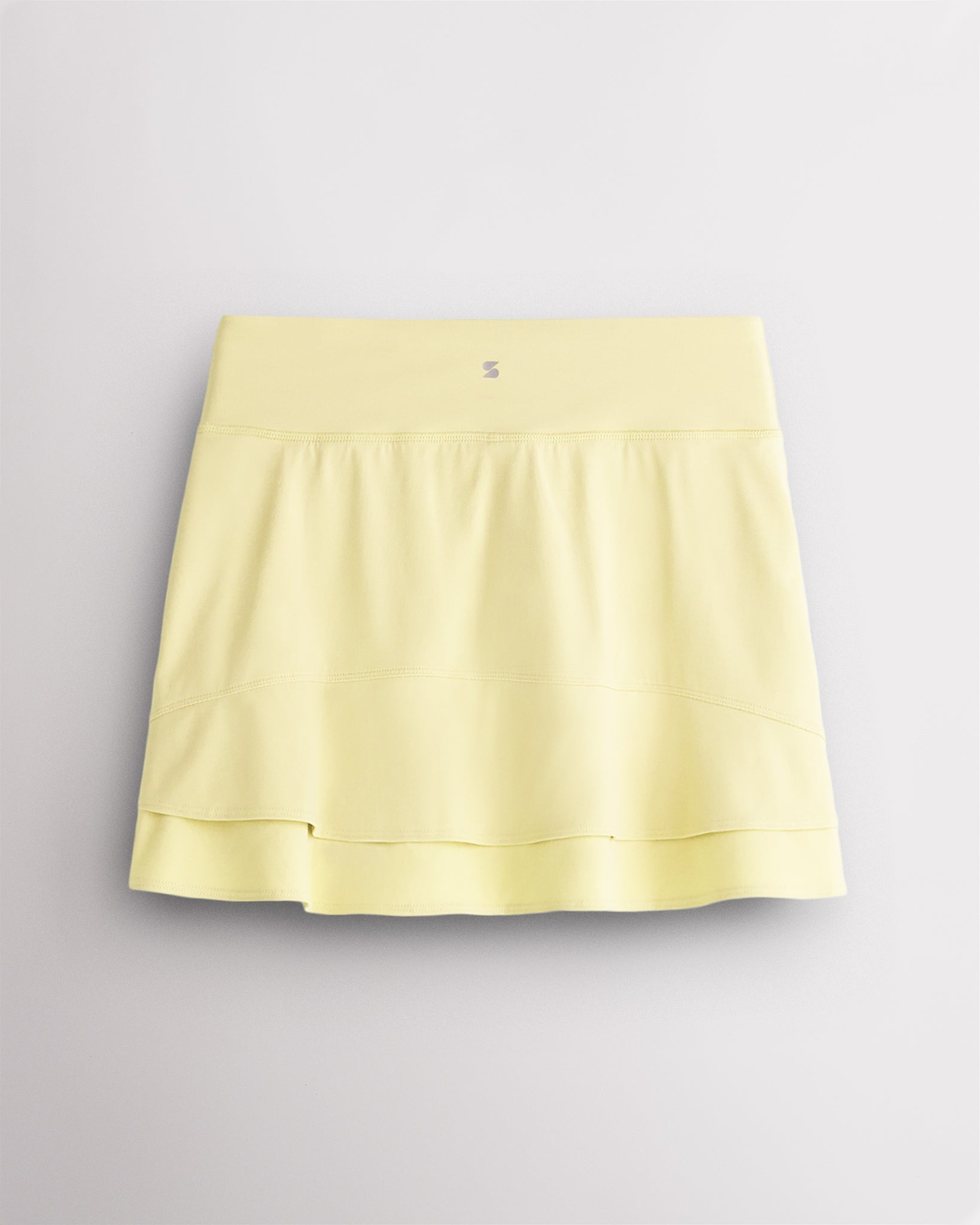 Back view of Lemon Butter Stelle Ruffle Ace tennis skirt showing double-layer ruffle detail, high waistband, and Stelle logo.
