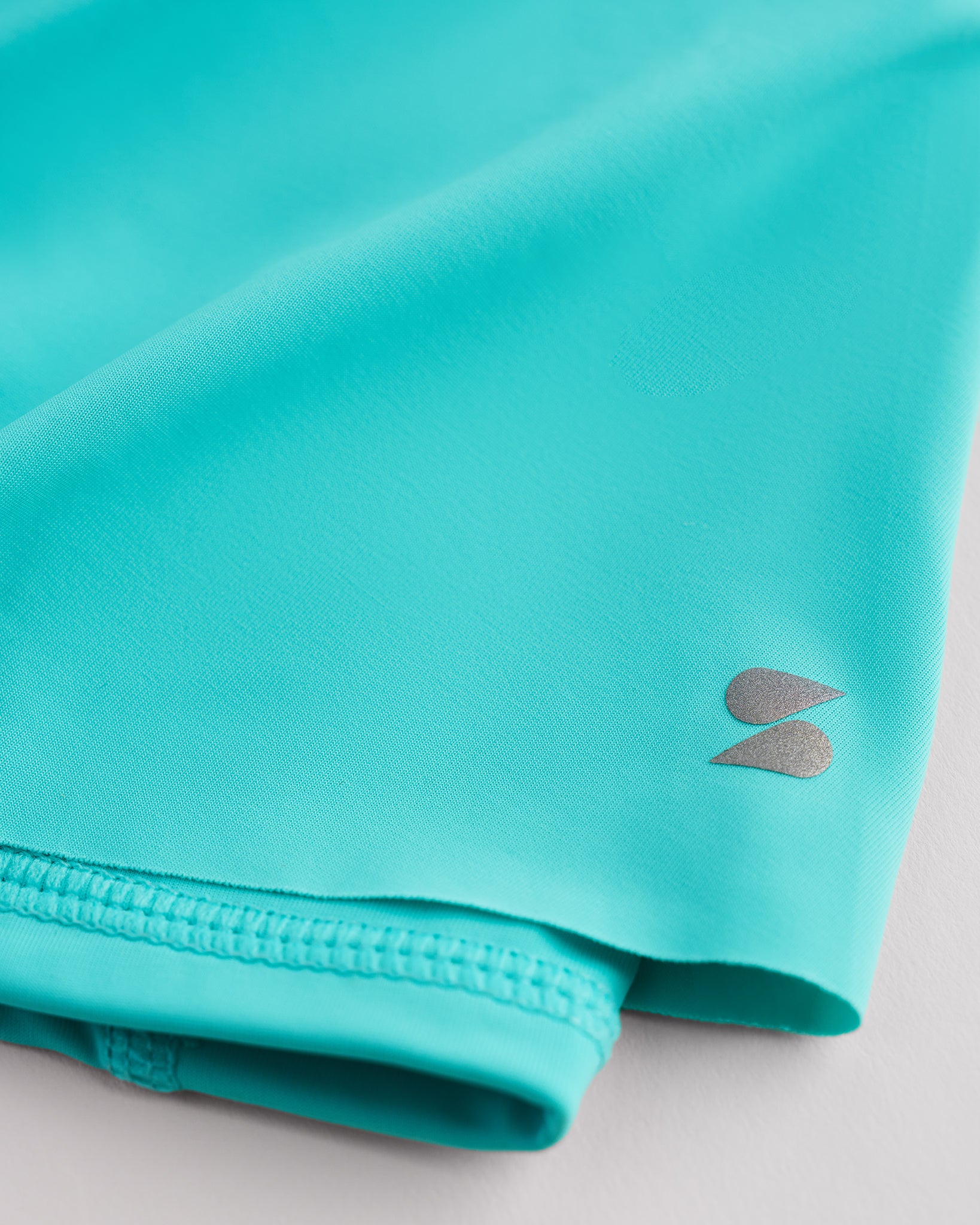 Close-up of aqua blue Kids Let’s Bounce Shorts showing lightweight quick-dry fabric, hem stitching, and small Stelle logo detail.