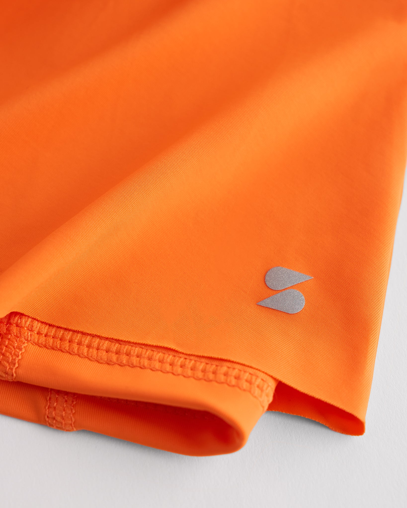 Close-up of orange Kids Let’s Bounce Shorts showing lightweight quick-dry fabric, hem stitching, and small Stelle logo detail.
