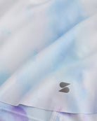 Close-up of Lilac Sky flowy shorts showing soft printed fabric, hem detail, and small Stelle logo.
