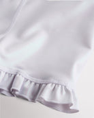 Close-up of white shimmer active shorts showing iridescent fabric and ruffle hem detail