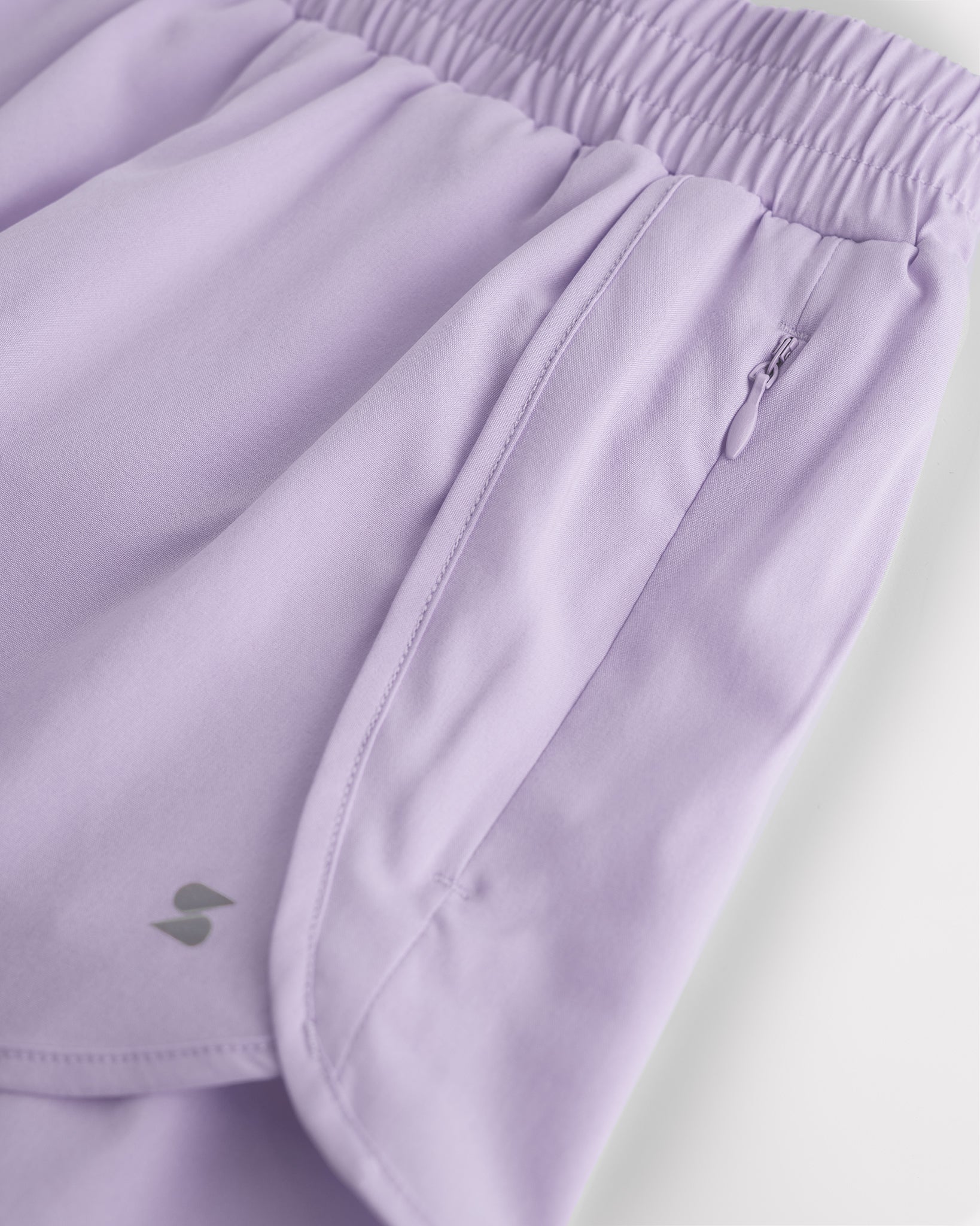Close-up of lavender girls running shorts showing zipper side pocket, curved hem, and smooth fabric for sports and everyday wear.