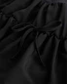 Close-up of black girls tennis skort showing layered chiffon fabric and adjustable tie detail