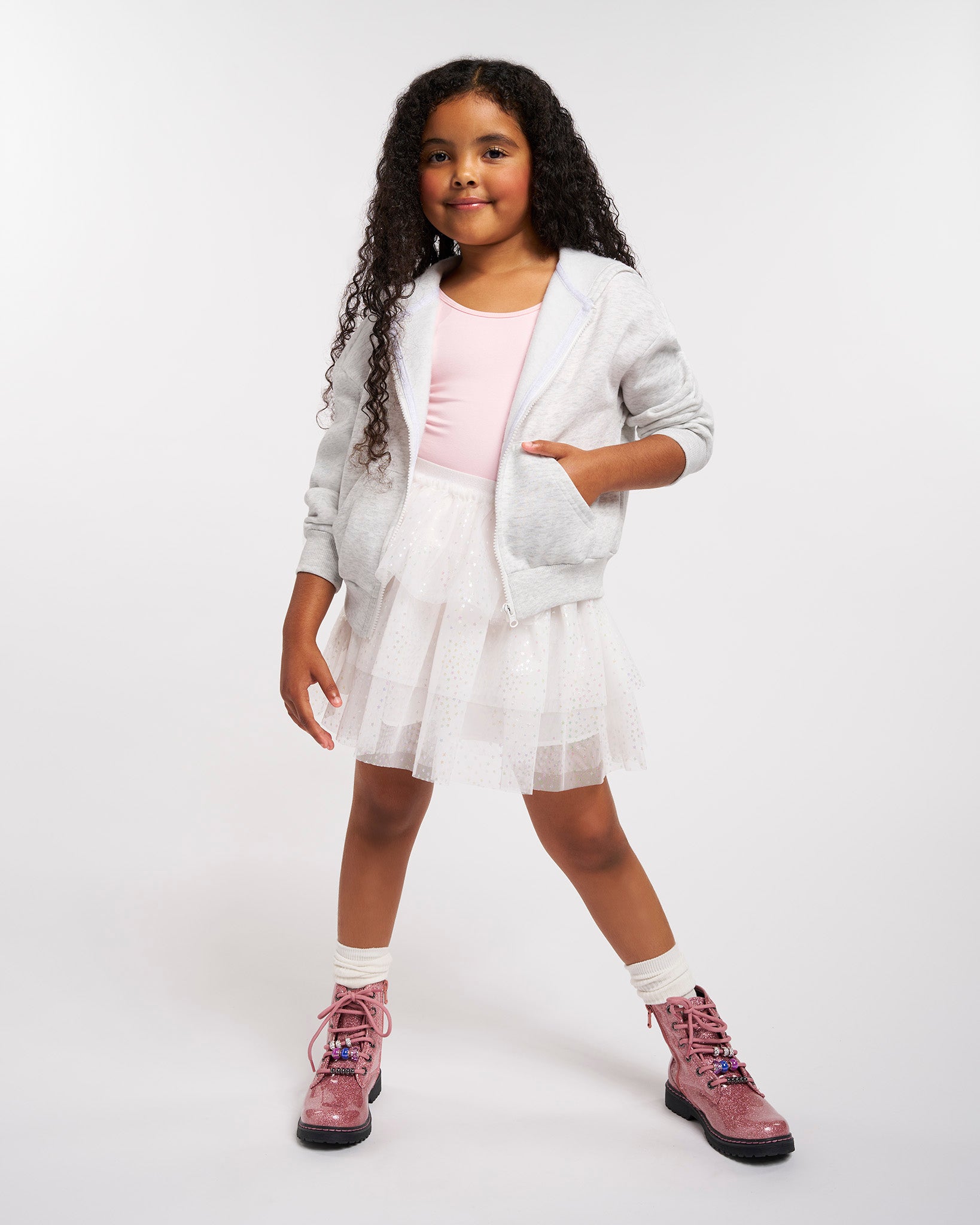 Young girl wearing a white outfit with pink boots on a white background