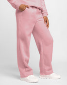Girl wearing pink kids fleece sweatpants with elastic waist, side pockets, relaxed fit, and white sneakers.