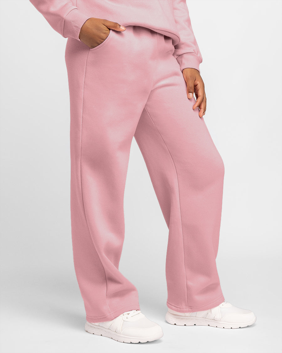 Girl wearing pink kids fleece sweatpants with elastic waist, side pockets, relaxed fit, and white sneakers.
