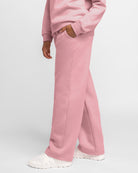 Side view of pink kids fleece sweatpants showing relaxed fit, side pocket, and straight-leg shape.