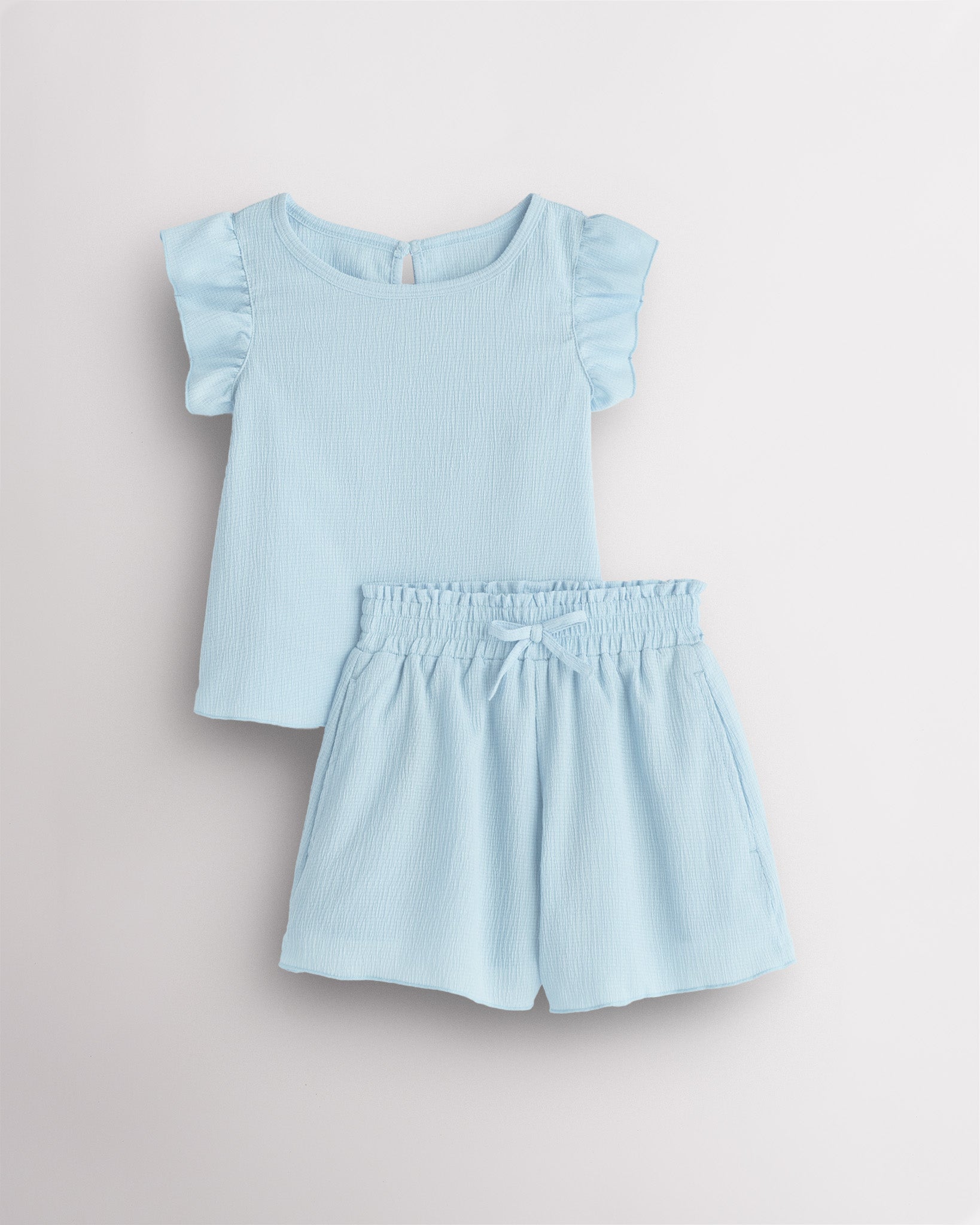 Girls light blue flutter sleeve summer outfit set with textured top, button-back detail, and matching elastic waist shorts with bow.