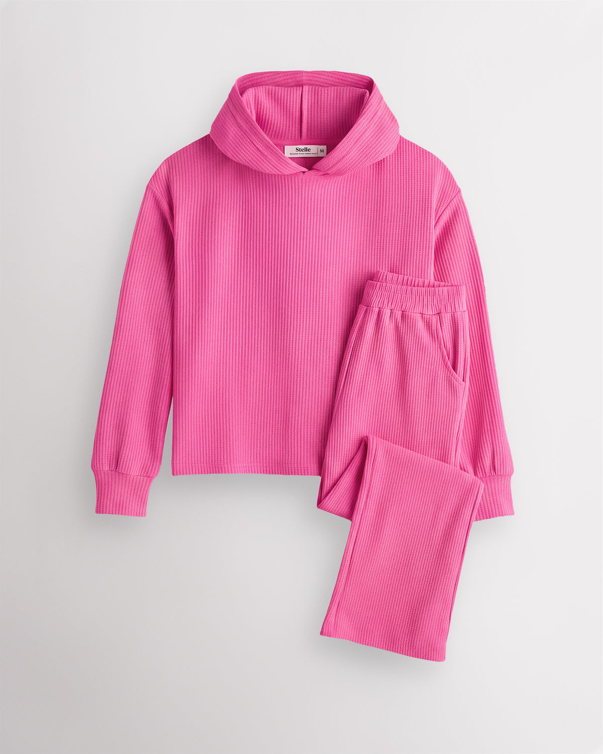 Dreamhouse Pink Stelle kids waffle knit lounge set with a hooded top and matching pants, laid flat on a grey background.