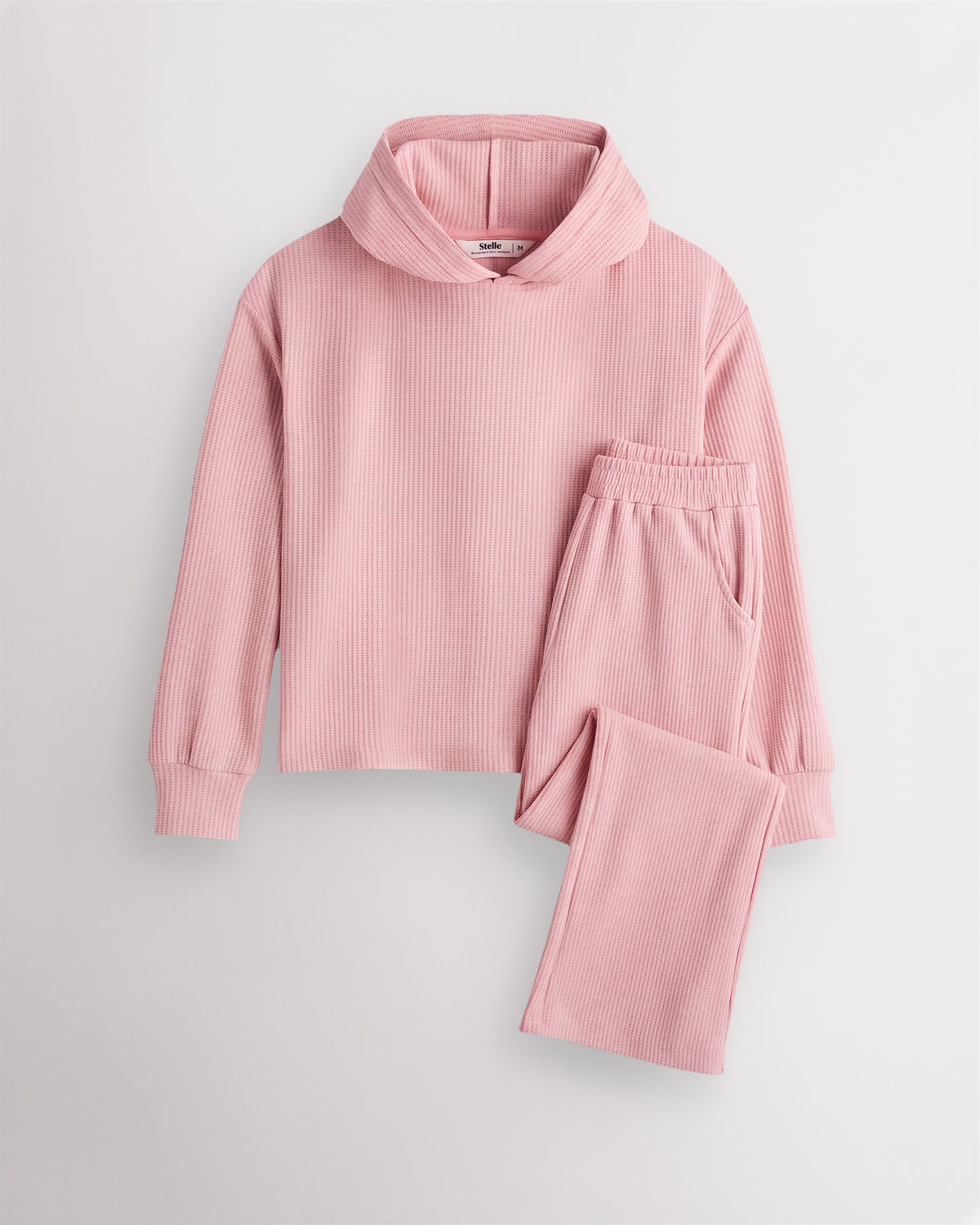 Dusty Rose Stelle kids waffle knit lounge set with a hooded top and matching pants, laid flat on a grey background.