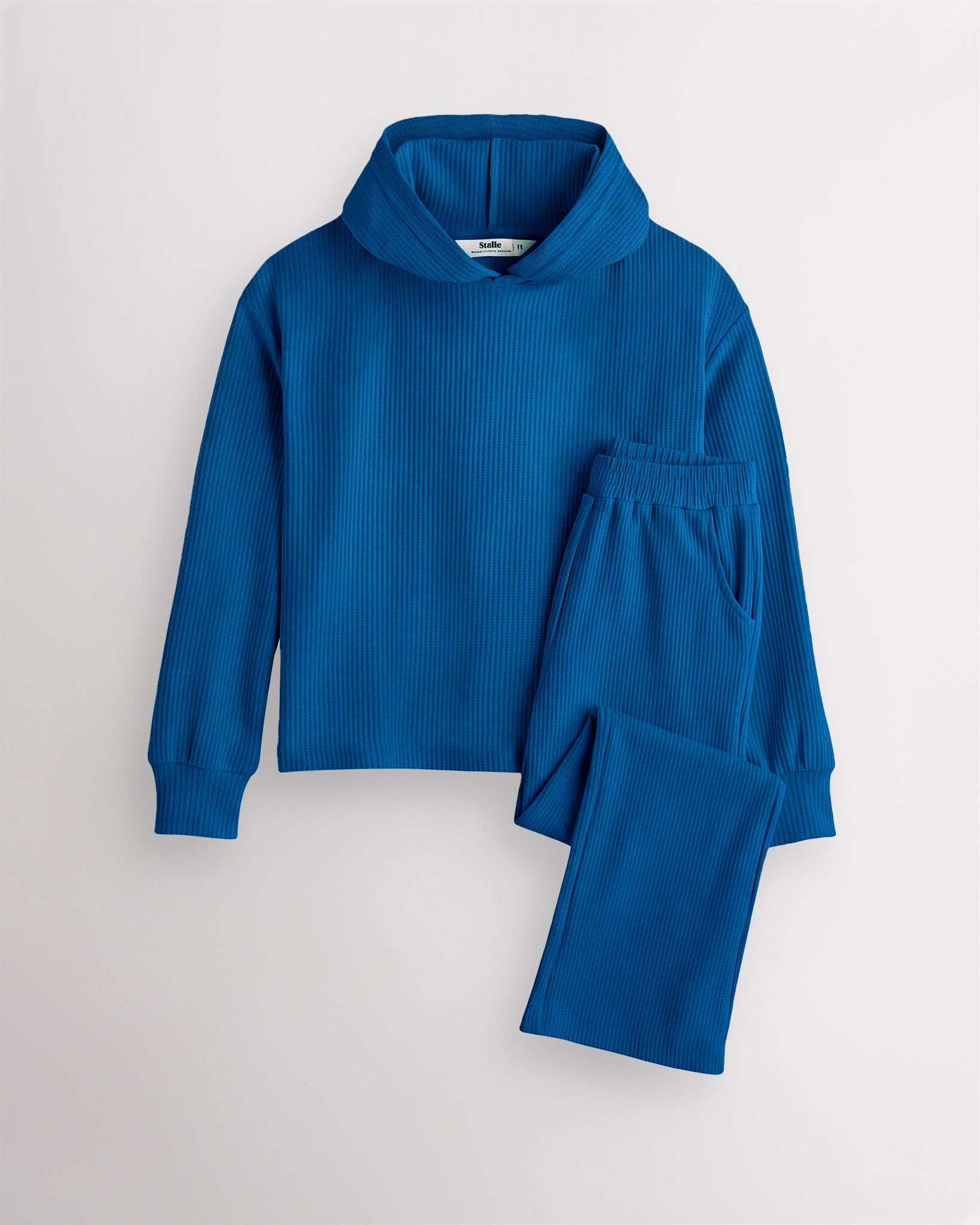 Navy Stelle kids waffle knit lounge set with a hooded top and matching pants, laid flat on a grey background.