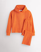 Orange Stelle kids waffle knit lounge set with a hooded top and matching pants, laid flat on a grey background.