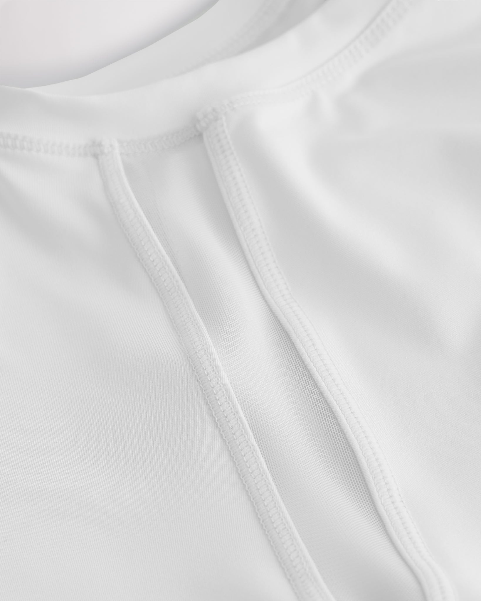 Close-up of kids athletic t-shirt mesh panel and flatlock seams showing breathable fabric and stitching detail.