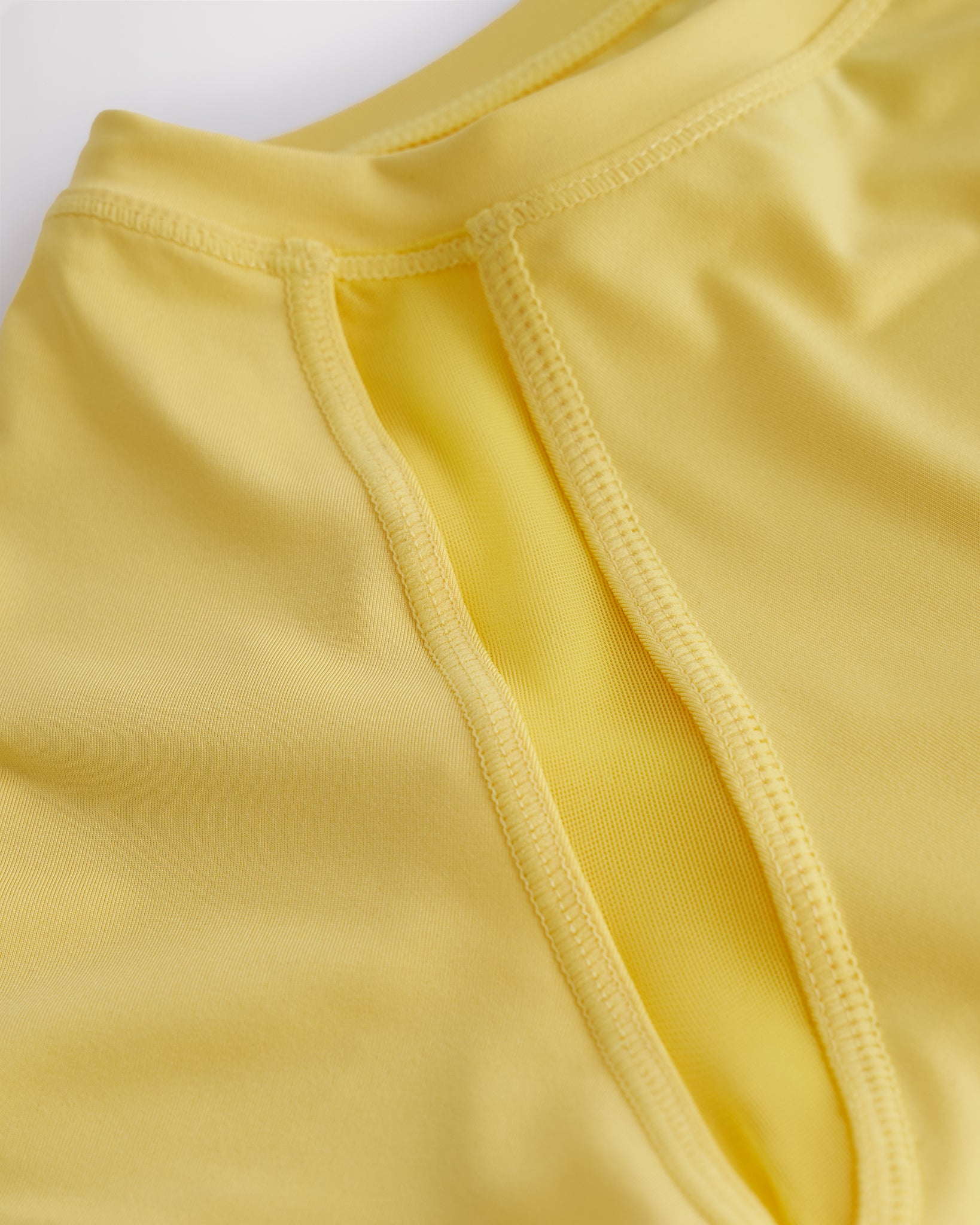 Close-up of kids athletic t-shirt mesh panel and flatlock seams showing breathable fabric and stitching detail.