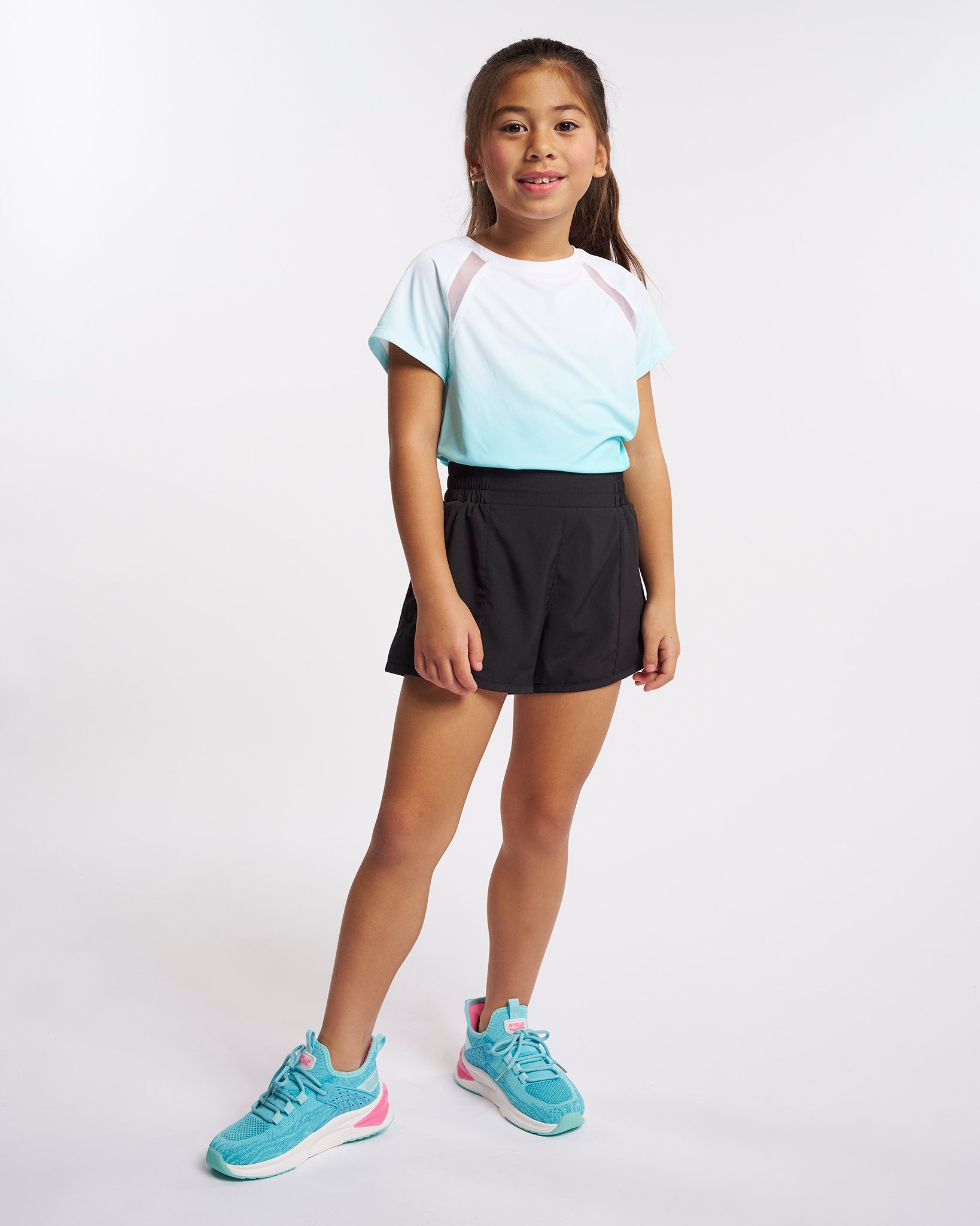 Girl wearing Stelle kids ombre athletic t-shirt with black shorts and aqua sneakers