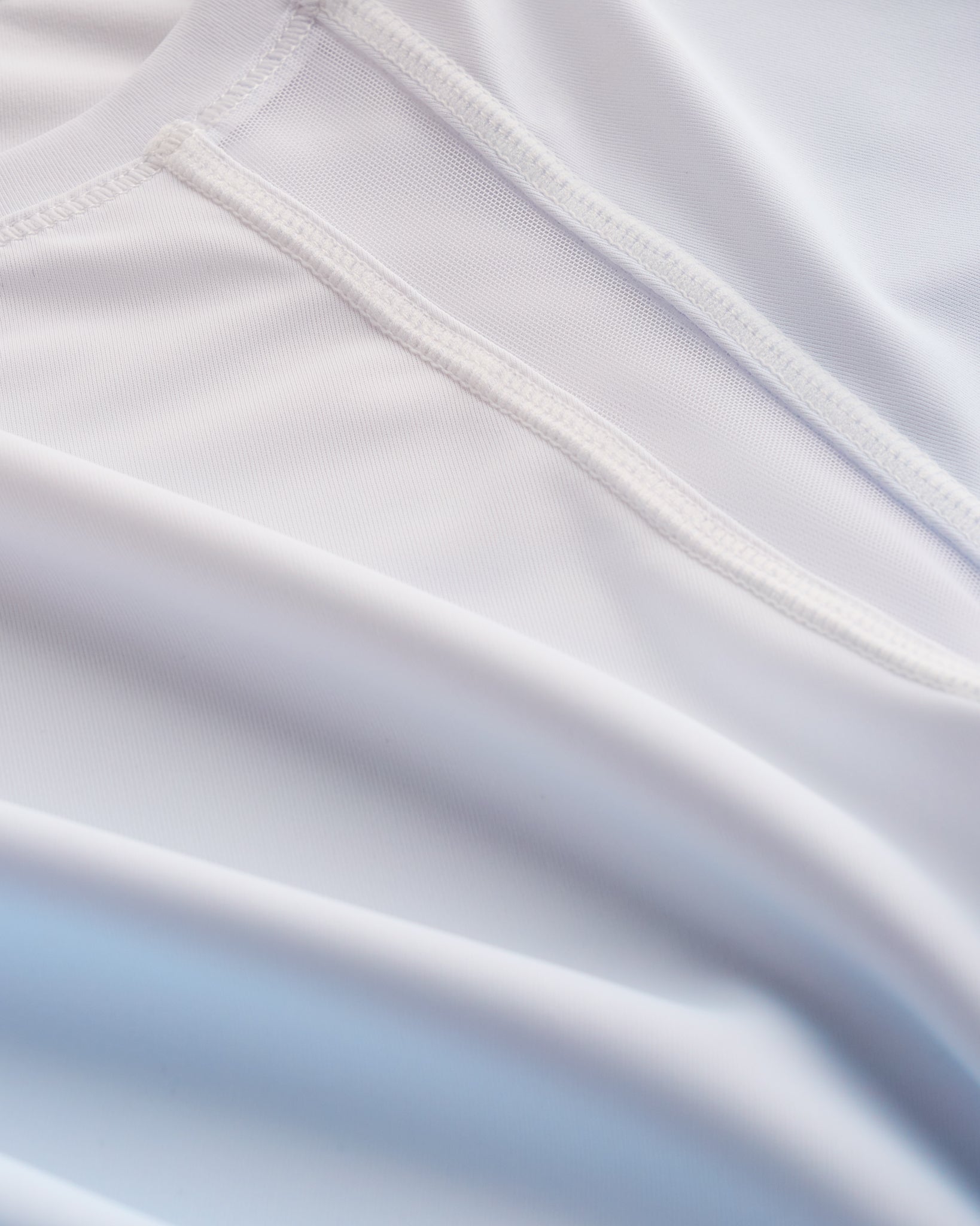 Close-up of Stelle kids ombre athletic t-shirt showing white mesh paneling, smooth seams, and light blue gradient fabric.