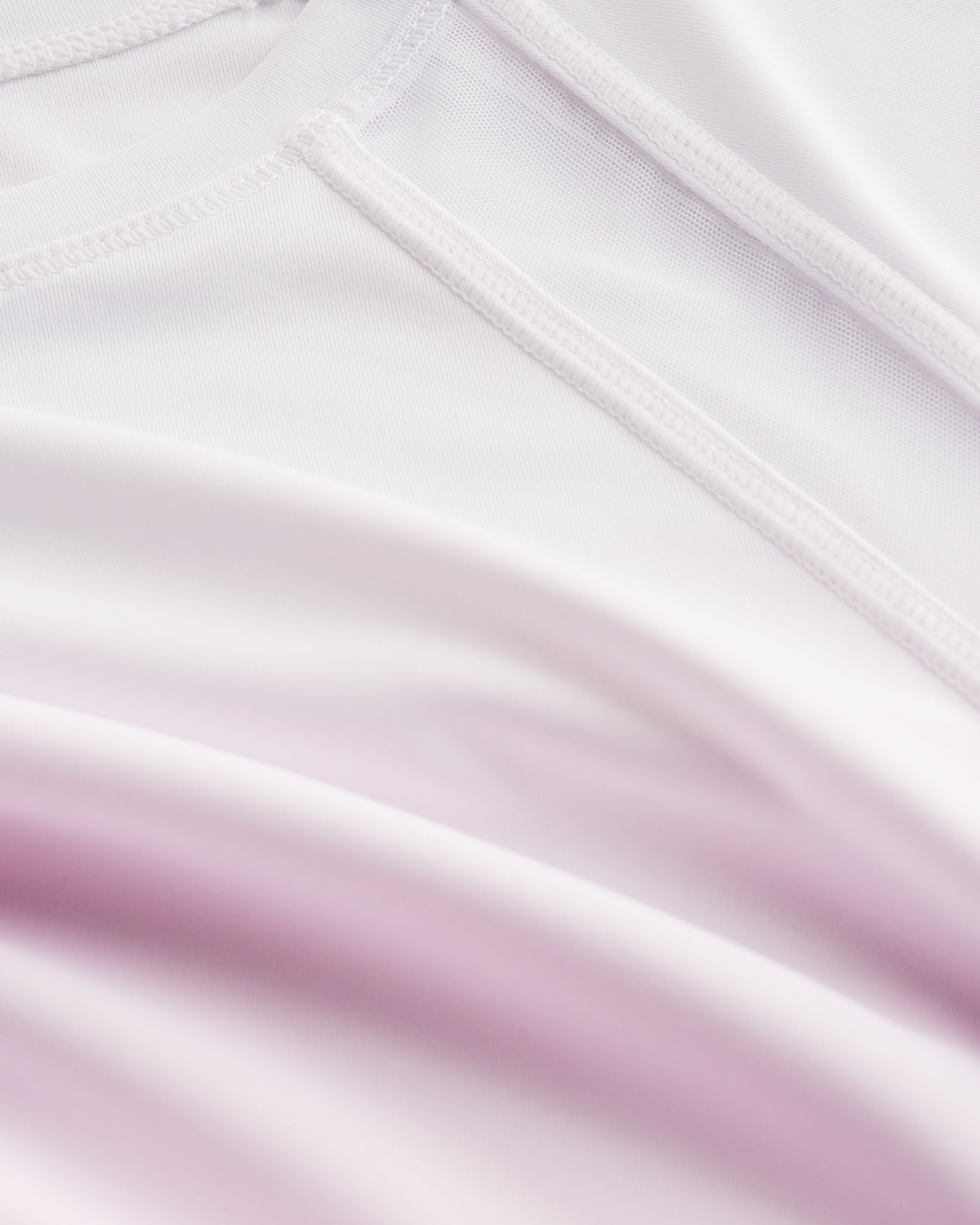 Close-up of Stelle kids ombre athletic t-shirt showing white mesh paneling, smooth seams, and pink gradient fabric.