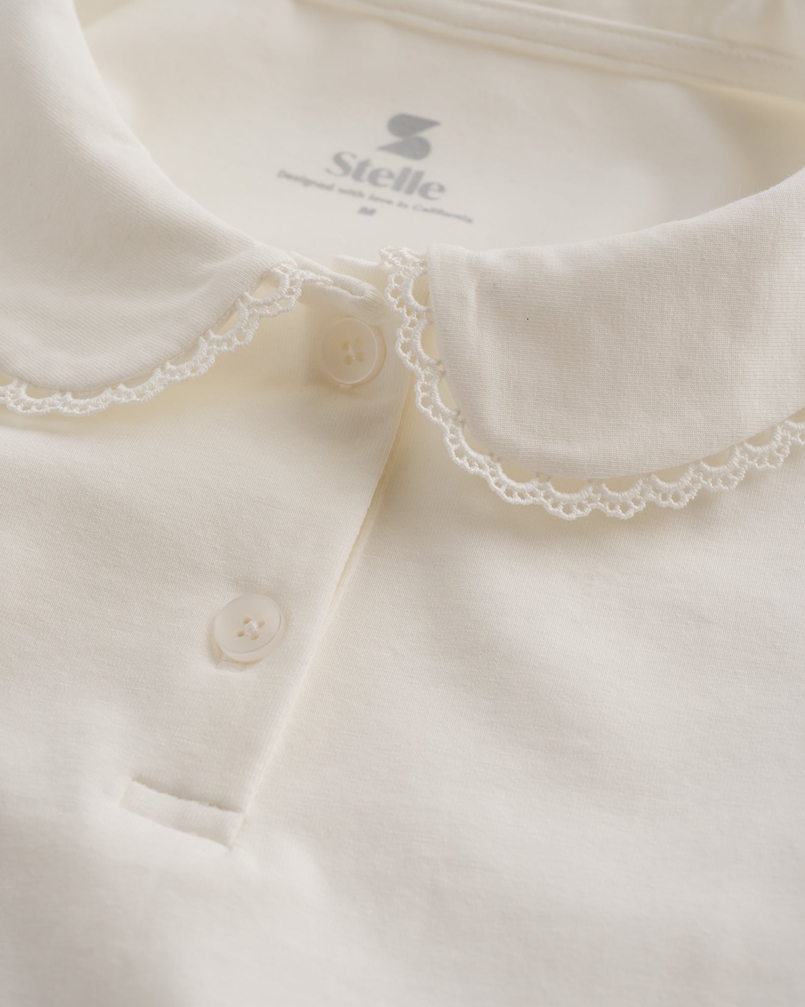 Close-up of white girls Peter Pan collar top showing delicate lace trim, button placket, and soft fabric.