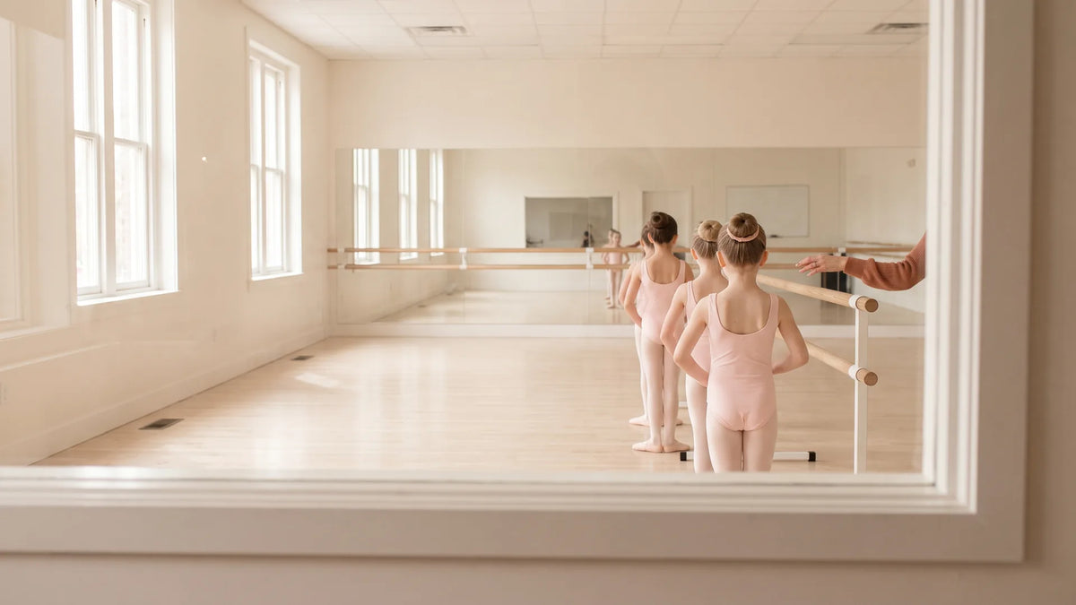 Young ballet students lined up at the barre during class, seen from the parent viewing window