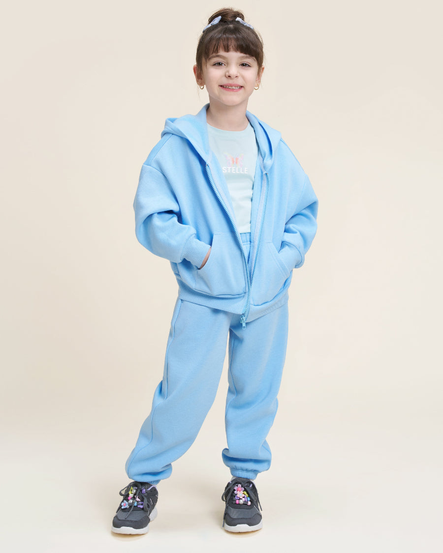 Child wearing a light blue tracksuit on a beige background