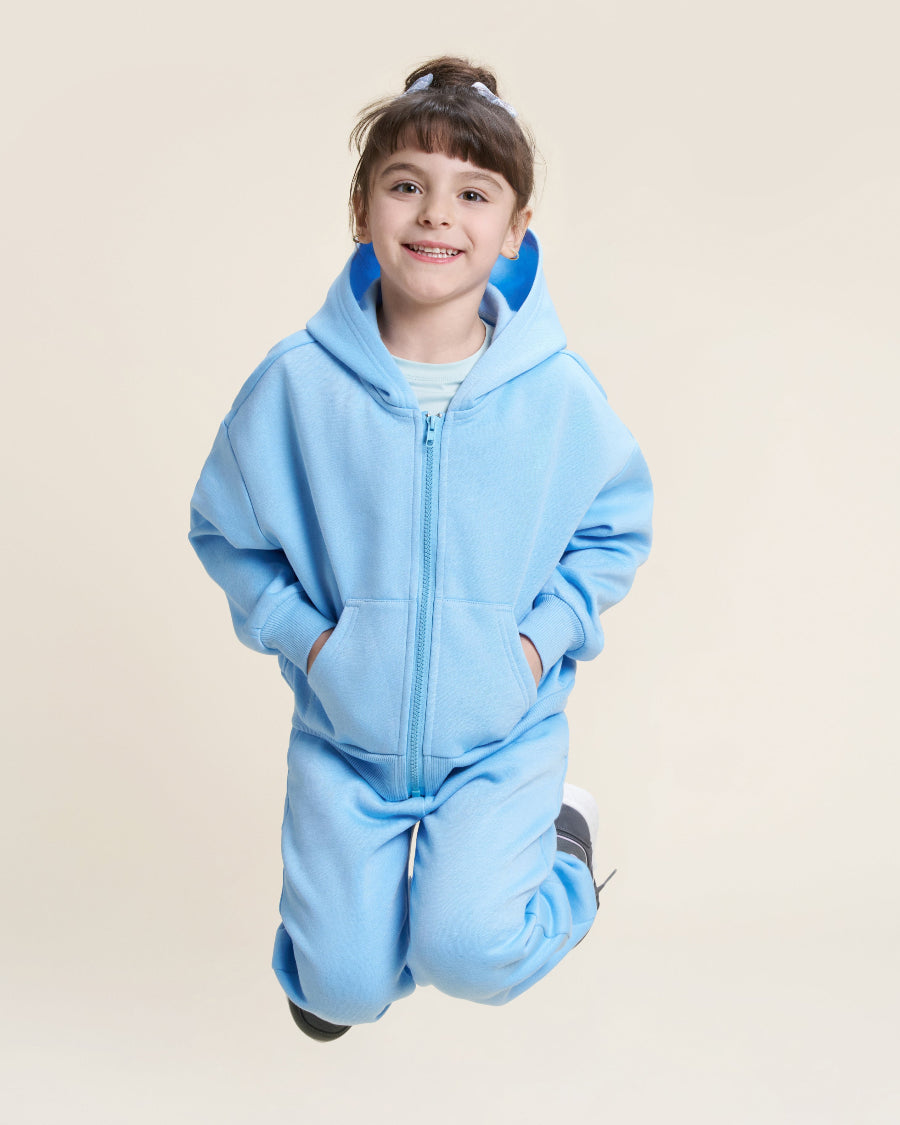 Child wearing a blue onesie against a beige background