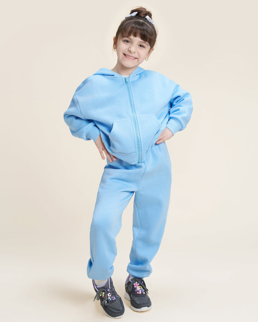Child wearing a light blue tracksuit on a beige background