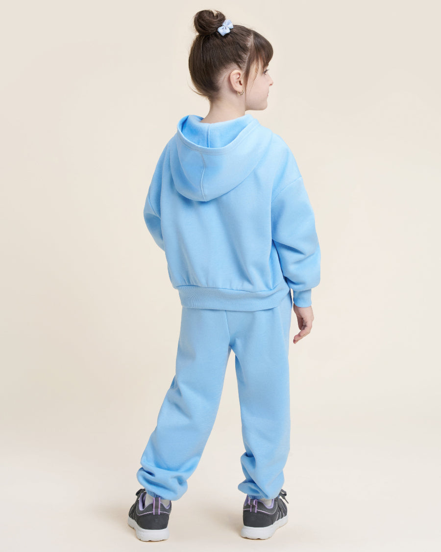 Child wearing a light blue tracksuit on a beige background