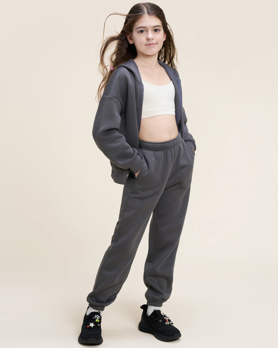Young girl wearing a gray tracksuit with a white top on a beige background
