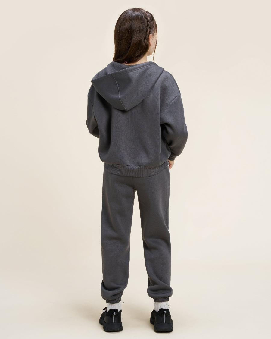 Person wearing a gray hoodie and pants on a beige background