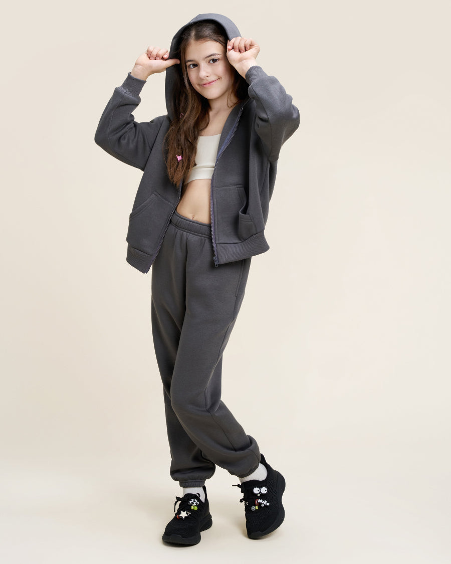 Person wearing a gray hoodie and pants on a beige background