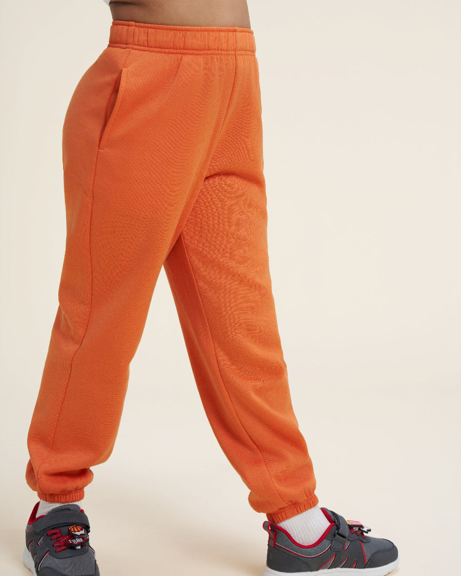 Orange sweatpants worn by a person on a beige background