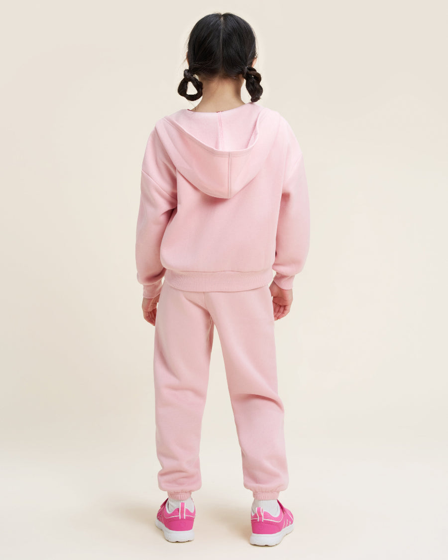 Child wearing a pink tracksuit on a beige background